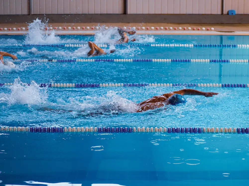 Young club swimmers racing freestyle in adjacent lanes at an indoor swimming gala
