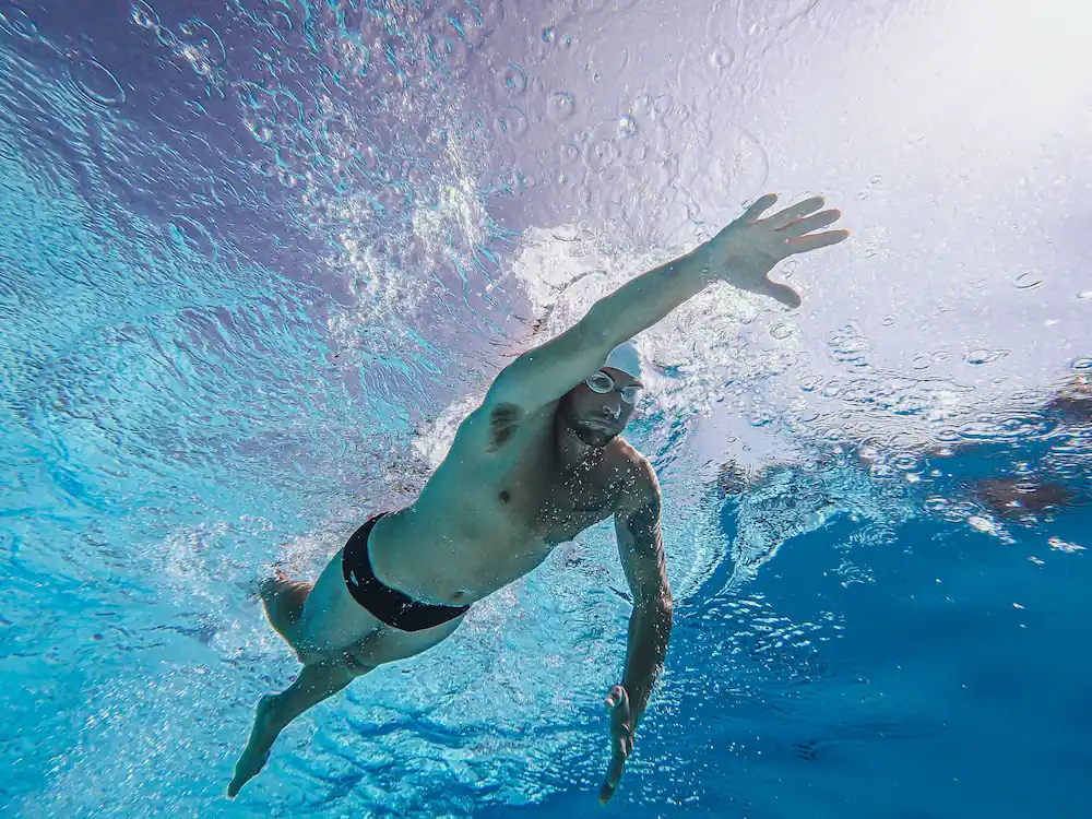 Underwater view of a front-crawl swimmer holding a high-elbow catch, forearm vertical and pressing straight back