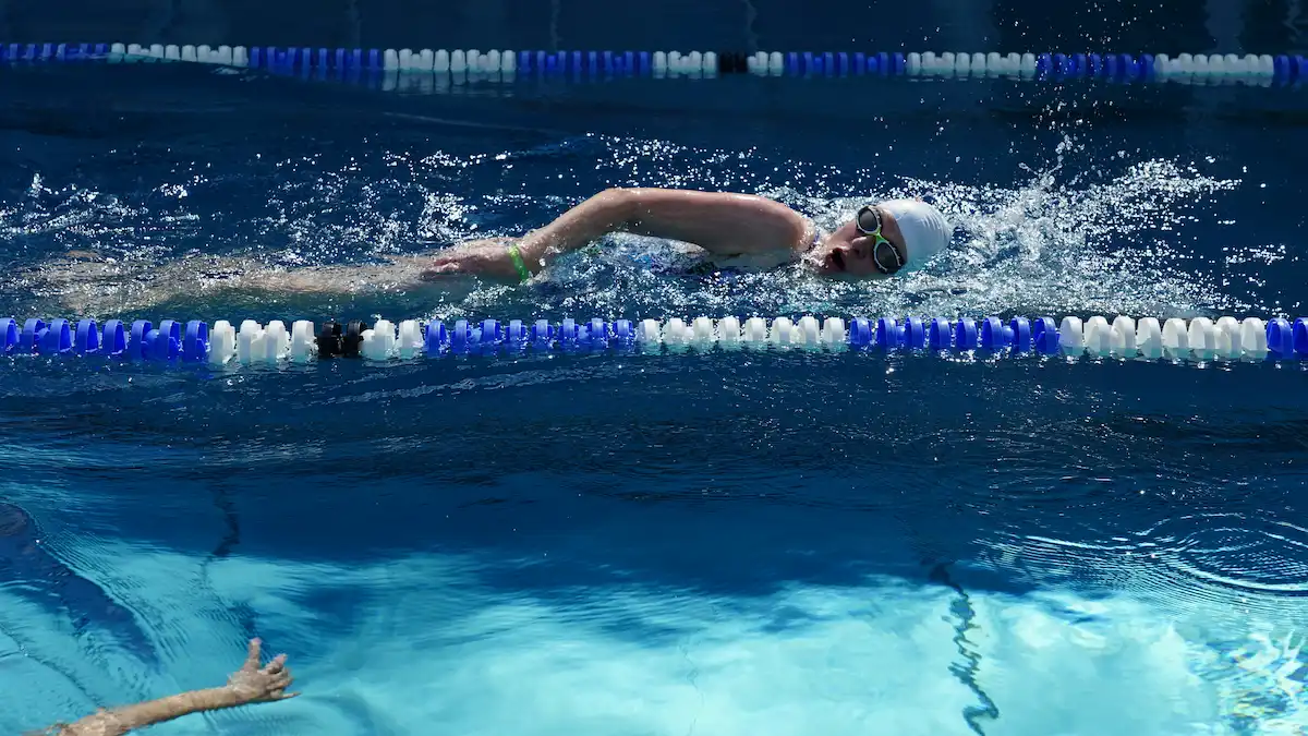 Swimmers in lanes at an outdoor pool at golden hour